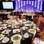 dining tables set in a ballroom with a lit stage